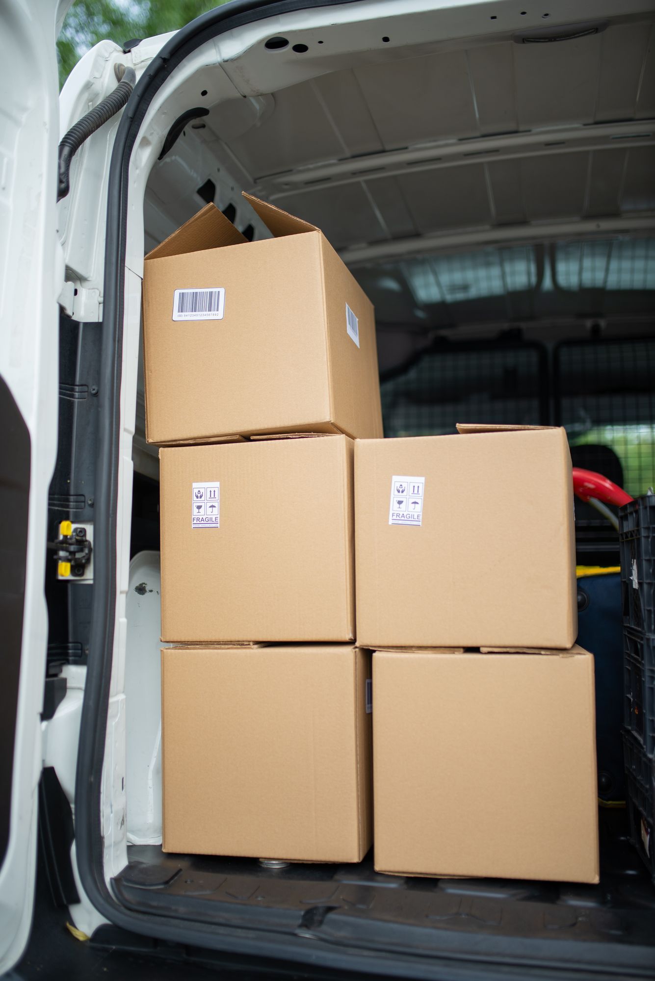 Brown cardboard cartons stacked inside the back of a delivery van.